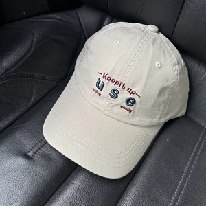 Detailed close-up of beige cotton baseball cap featuring high-quality 3D letter embroidery
