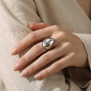 Detailed close-up of a silver polished chunky curved stainless steel ring on model's finger