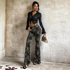 Detail of black lace cropped top and rhinestone zebra print flared trousers on a model