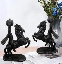 Detail showing two headless horseman resin statues with pumpkins on a desk setup