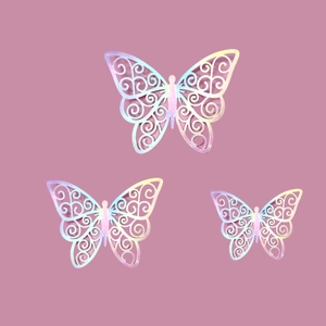 Detailed laser-cut butterfly cake toppers with iridescent hollow design on pink background