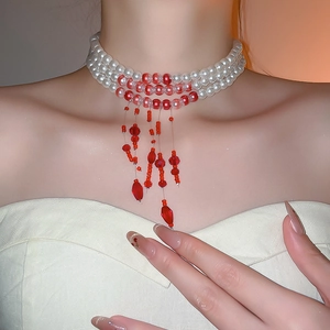 Detailed view of multilayer pearl necklace with red bead fringe and elegant tassel pendant