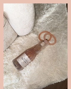 Close-up of sparkling rose gold rhinestone wine bag holder on plush beige carpet