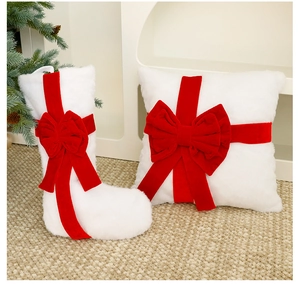 Close-up of plush white Christmas stocking and pillow with large red velvet bows