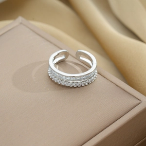 Detail of silver double-row open ring with sparkling crystal stones on a beige jewelry box