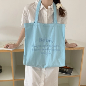 Detailaufnahme der hellblauen Segeltuchtasche mit feiner Bebe-Zitat-Stickerei