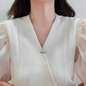 Detailed view of sailboat brooch with white crystals on elegant v-neck outfit