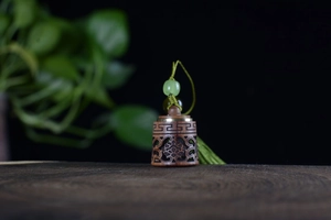 Detail of hand-carved sandalwood sachet pendant with green beads and long tassels