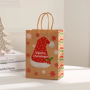 Detail of kraft paper Christmas gift bag with Santa hat, snowflakes and red striped sides