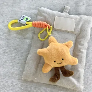 Dettaglio del portachiavi a stella in peluche giallo con ricamo e cordino arancione
