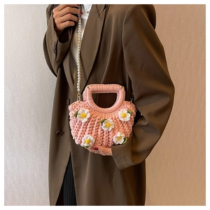 Detail of handmade pink crochet shell bag with floral accents and elegant pearl strap