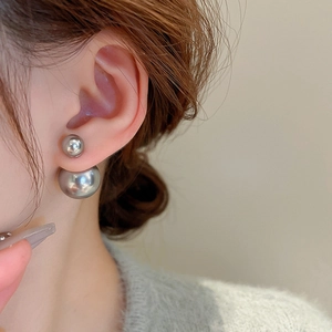 Close-up of elegant silver-grey double pearl earrings worn by a model on a beige background