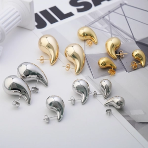 Macro view of teardrop stud earrings in gold and silver finish with high mirror polish