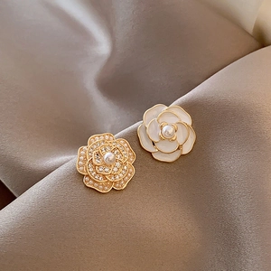 Detailed macro view of camellia stud earrings with pearls and rhinestones on silk
