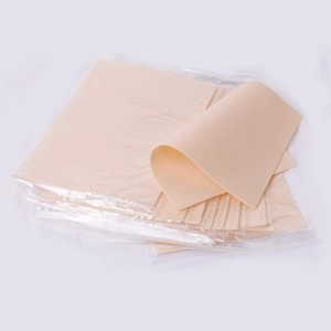 Stack of beige silicone tattoo practice skin sheets individually wrapped in clear plastic