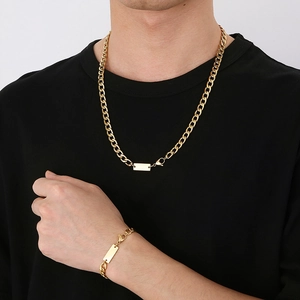 Gouden titaniumstalen NK-ketting en armbandset met vierkant label gedragen door model