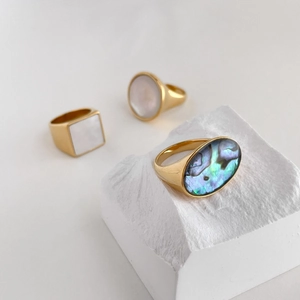 Detail of gold rings set with natural abalone and white mother of pearl geometric shells