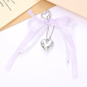 Detail of lavender plaid ribbon bow and pearl chain on a silver heart bag charm