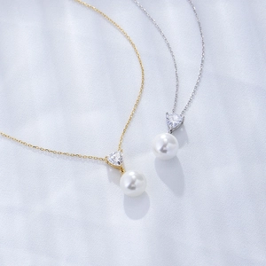 Detail of silver and gold pearl necklaces with triangle zircon pendants on blue silk