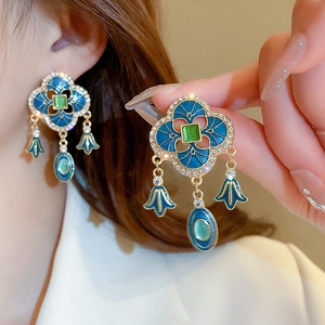 Detail of vintage palace style earrings with blue enamel and green gemstone drop