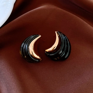 Detailed view of crescent moon earrings in black resin with 18K gold-plated metal trim
