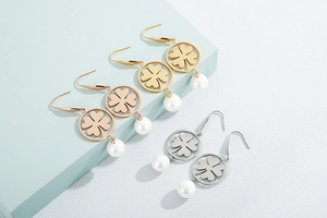 Detail of clover hollow earrings with white pearls in gold, rose gold and silver