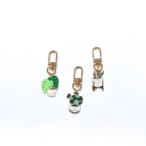 Detailed set of three green plant enamel keychains with monstera and pilea charms