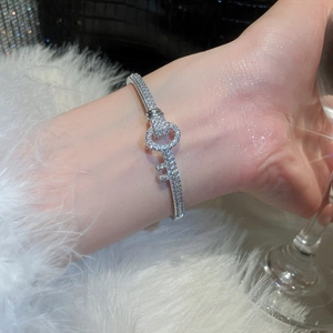 Macro shot of silver key bangle with pavé zirconia crystals on white faux fur background
