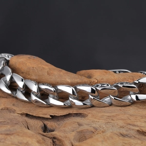 Macro shot of vintage engraved silver Cuban link chain over a dark wooden background