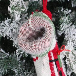 Knitted Christmas stocking gift bag in red, white and green hanging on a tree
