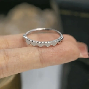 Detailed view of silver heart shaped pattern ring worn on finger with blurred background