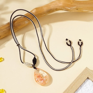 Macro view of teardrop natural crystal pendant with internal inclusions on woven cord