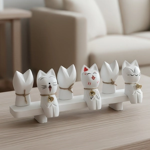 Set of 6 minimalist white ceramic cat figurines with bells on a light wood table