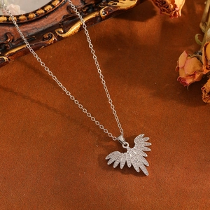 Macro shot of silver wing-shaped pendant necklace with cubic zirconia on textured background