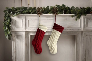 Classic cable knit Christmas stockings in red and cream hanging on a white fireplace