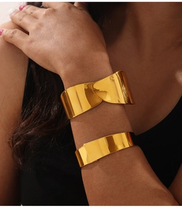 Detail of double-layered gold geometric bangles worn on wrist with polished finish
