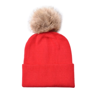 Detailed close-up of a red knit beanie featuring a large removable faux fur pompom decoration