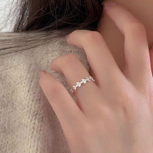 Macro shot of 925 sterling silver olive leaf ring worn on hand with cozy knitwear background