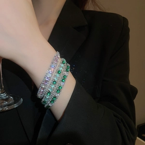 Close-up of four cubic zirconia tennis bracelets in pink and green on a model's wrist