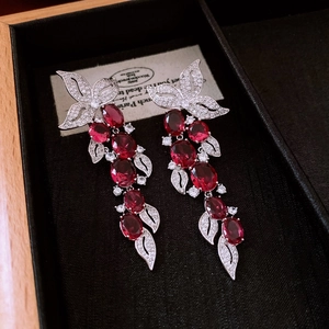 Detail of vintage leaf tassel earrings featuring red crystal stones and zircon inlay