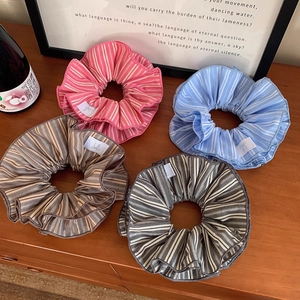 Lot de quatre chouchous rayés en rose, bleu, kaki et gris sur une table en bois clair