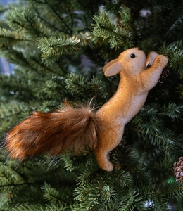 Close-up of a realistic squirrel ornament with fluffy fur hanging on a Christmas tree