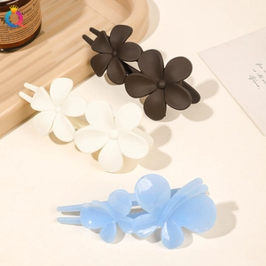 Detail of floral matte hair clips in dark brown, beige, and light blue on a stylish tray