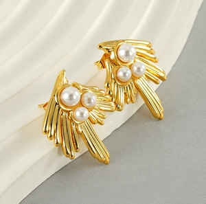 Detail of 18K gold swallow-style earrings with abstract wings and white pearls