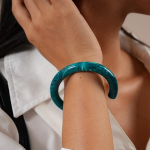 Detail of teal marble acrylic open bangle showing smooth texture on woman wrist