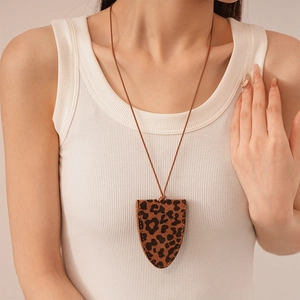 Close-up of leopard print shield pendant necklace on model wearing white ribbed top