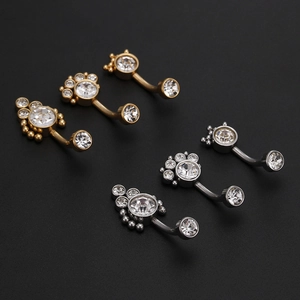 Detail of gold and silver navel rings with crown, paw print, and zircon cluster designs