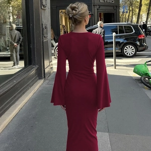 Détail macro d'une robe longue bordeaux avec manches cloches évasées et tombé élégant