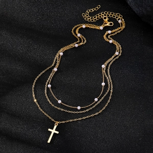 Three-layer gold necklace featuring faux pearl beads and a minimalist cross pendant