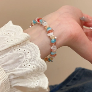 Macro shot of colorful irregular stone beads on a sweet style bracelet with lace cuff